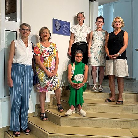 Mitgliederinnen des Landshuter Frauenplenums stehen auf Treppen neben Gedenktafel für Dr. Hildegard van Straelen (von links nach rechts: Hedwig Borgmann, Elke März-Granda, Patricia Steinberger, Anja König, Iris Haas). In der Mitte sitzend die Enkelin der Geehrten.
Foto © Katrin Weinzierl